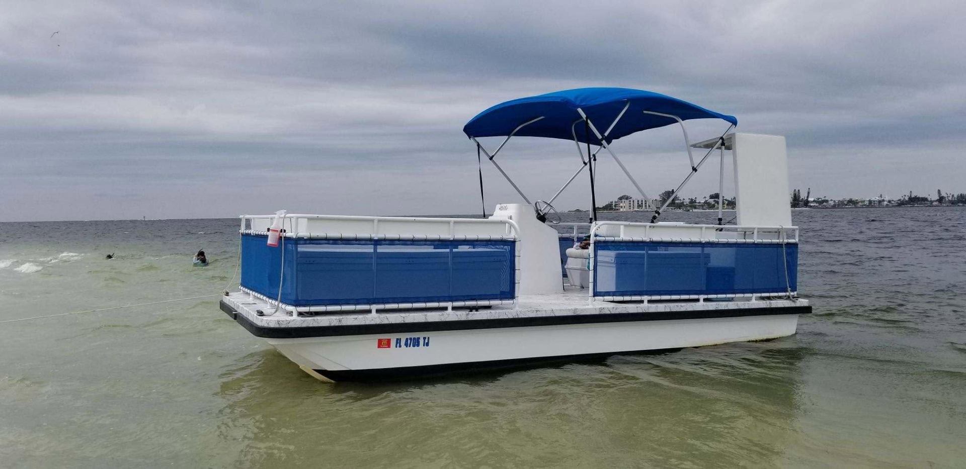 Marine13 pontoon charter boat anchored off the beach